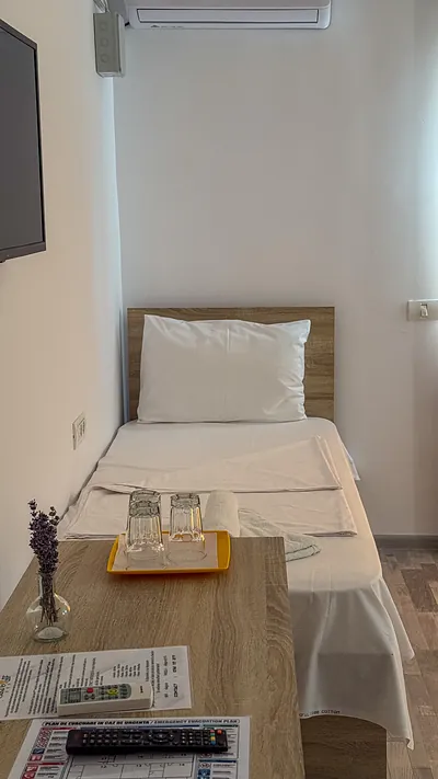 Patul single dintr-o cameră triplă, cu lenjerie curată și prosoape